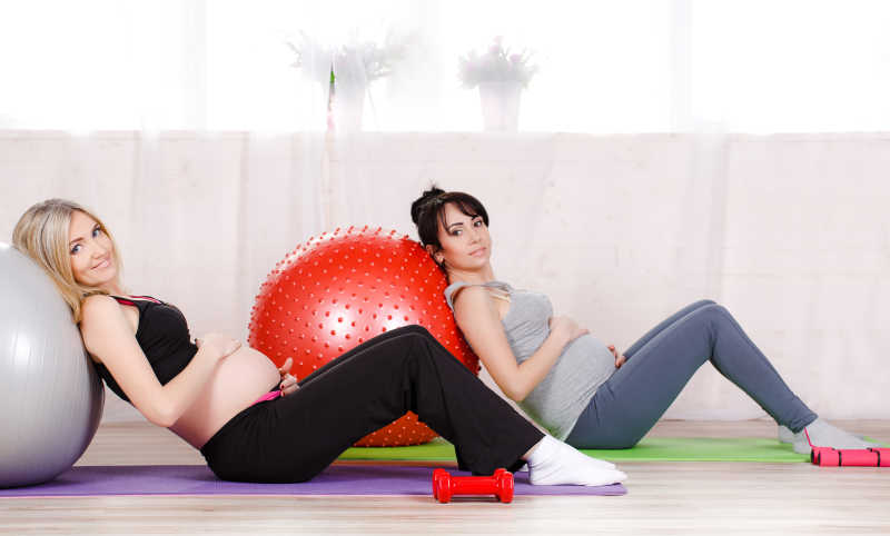 靠在瑜伽球上练习瑜伽健身运动的孕妇