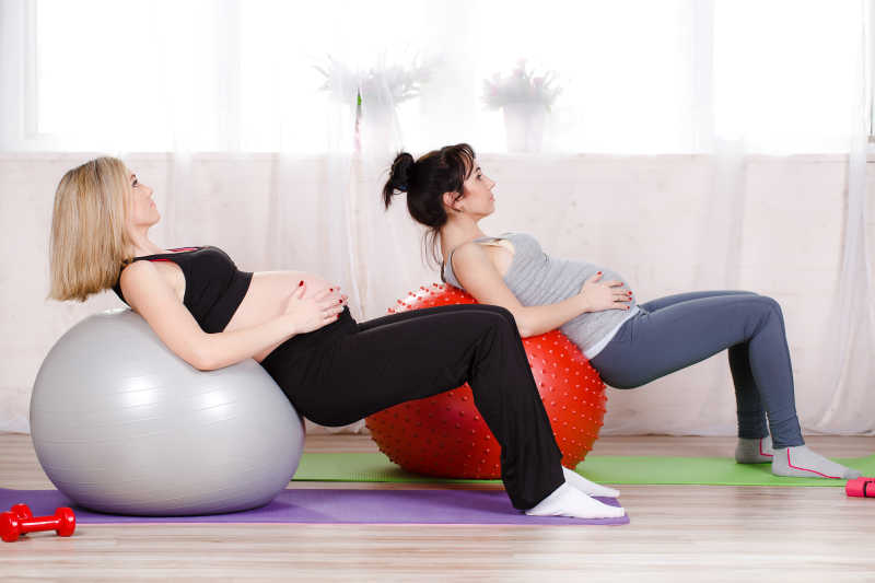 靠着瑜伽球练习健身伸展运动的孕妇