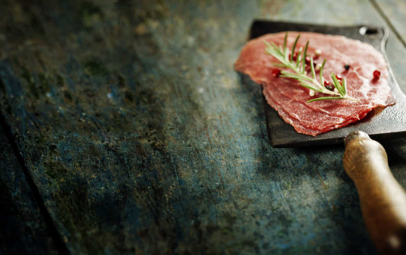 切肉刀和牛肉在黑暗的餐桌上