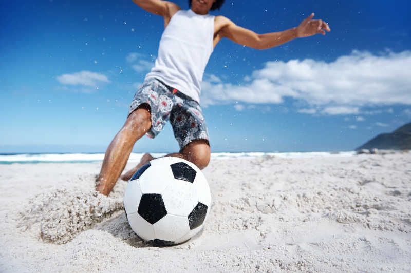 动感的沙滩上踢足球的人
