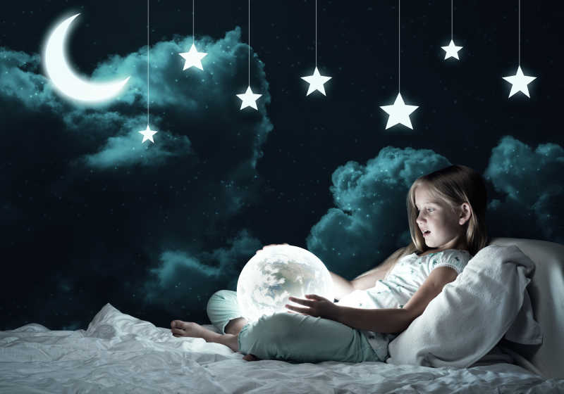 女孩儿抱着发光的地球仪在床上