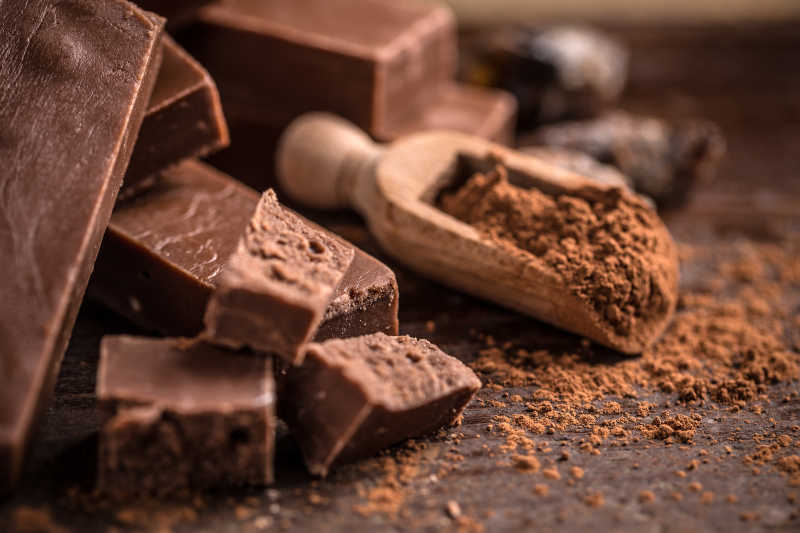 棕色背景中破碎的巧克力棒和可可粉