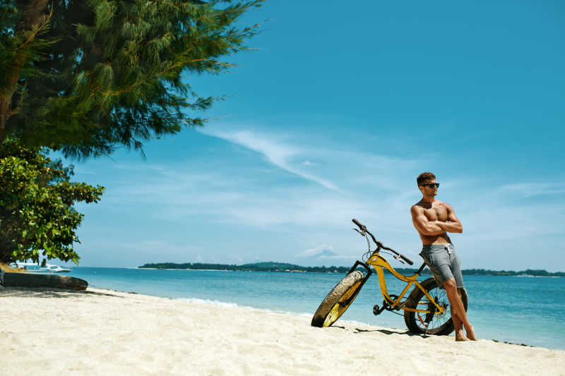 健身男子骑自行车在海边享受日光浴
