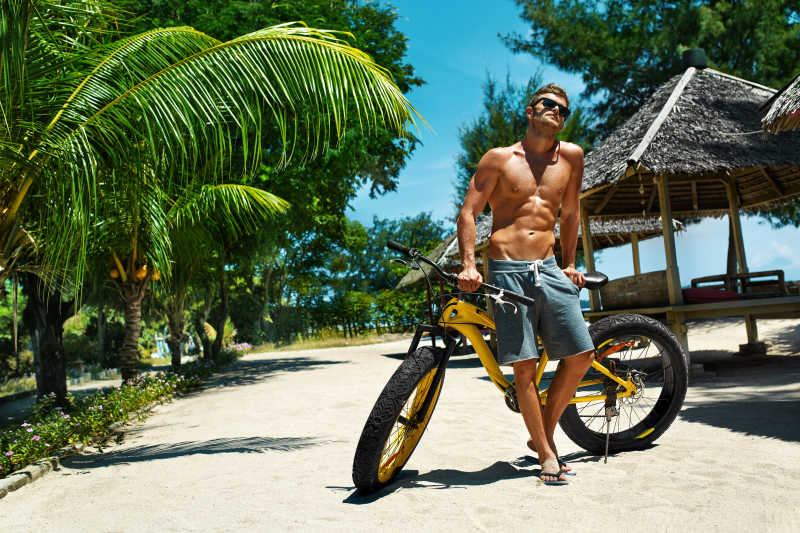 在热带海滩度假的帅哥骑自行车
