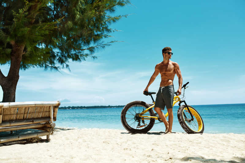海边沙滩上靠着自行车的帅哥