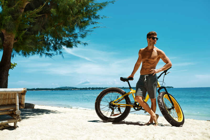 夏日沙滩上的英俊帅哥骑自行车
