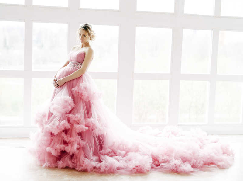 美丽的孕妇穿着粉红色华丽连衣裙