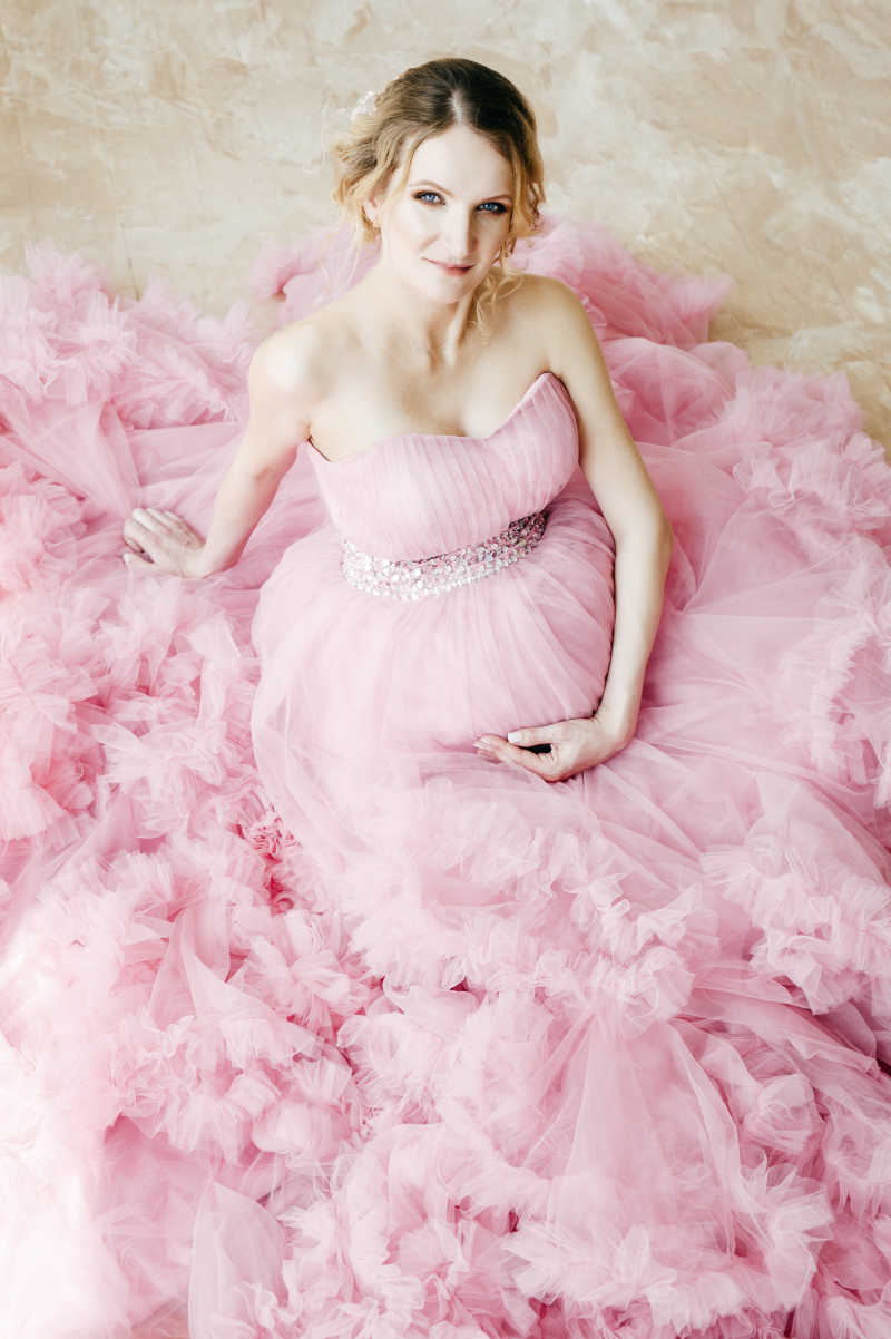 穿着粉红色华丽连衣裙的美丽孕妇
