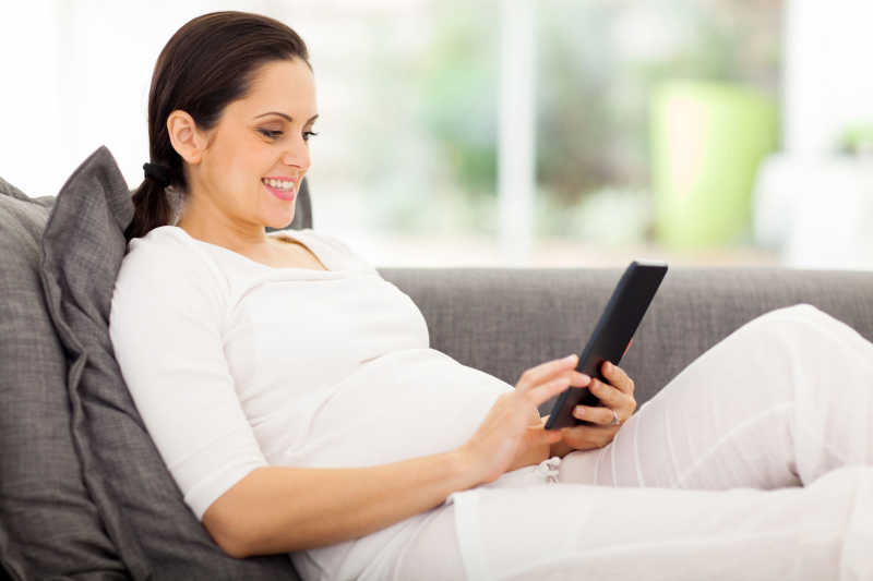 快乐的孕妇使用平板电脑