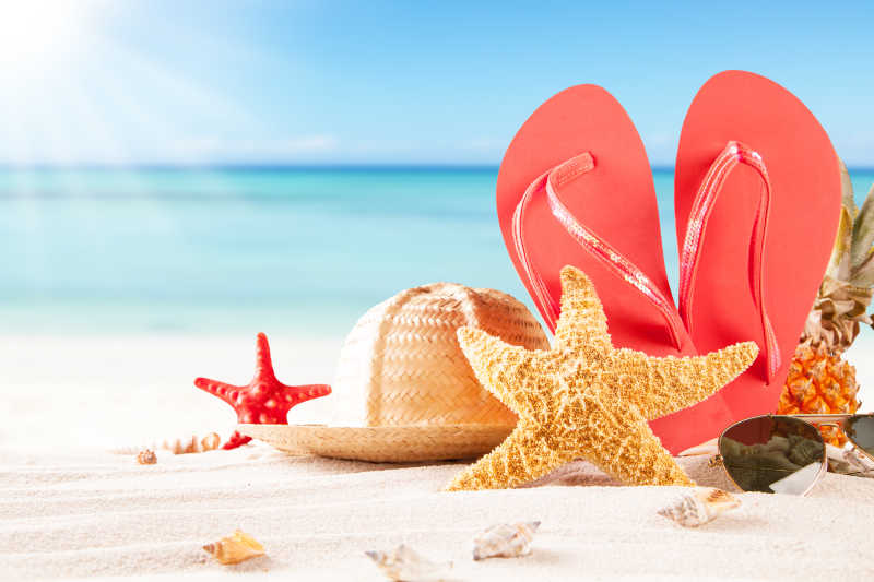 夏日沙滩上的草帽贝壳和凉鞋