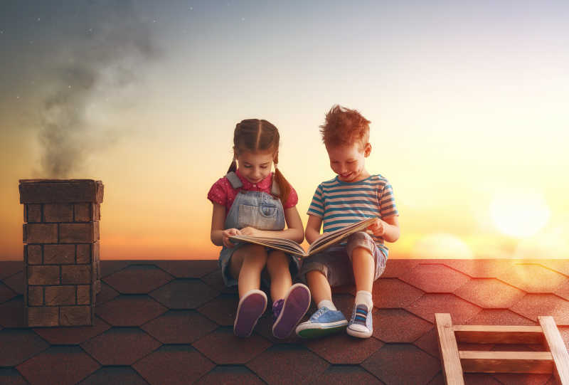 夕阳下坐在屋顶上读书的孩子们