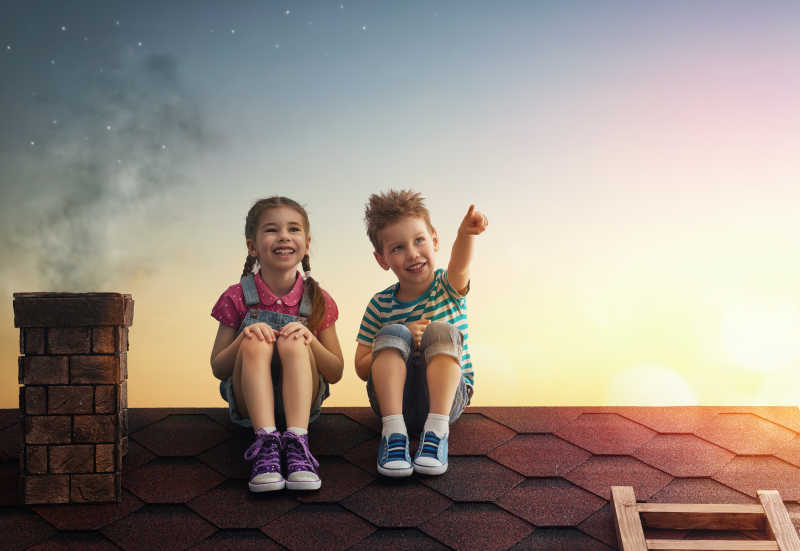 男孩和女孩坐在屋顶上看着星星