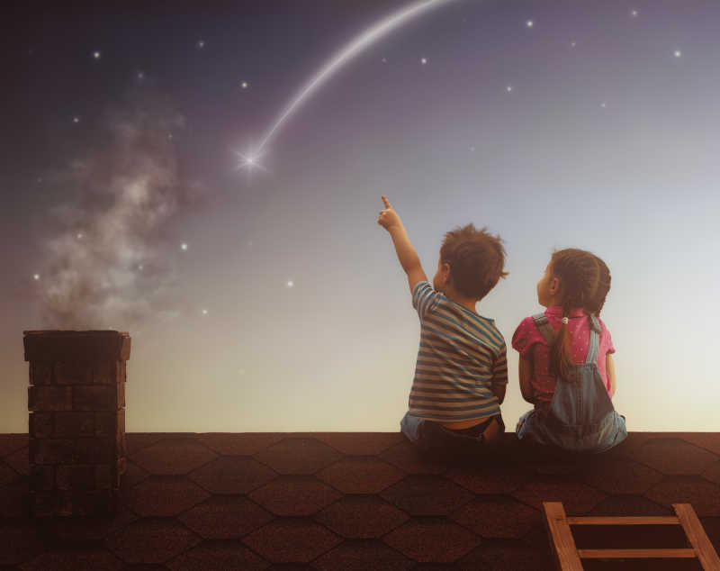 两个可爱的孩子坐在屋顶上看流星