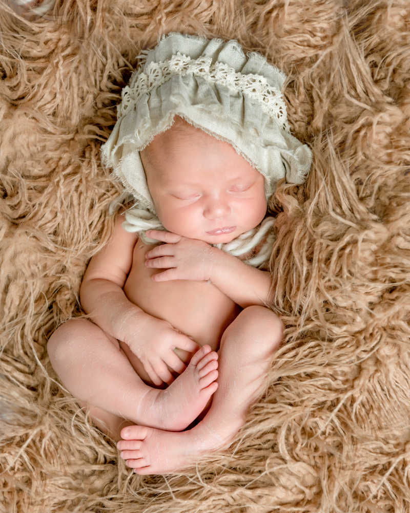 睡在松软的毯子上戴帽子的初生婴儿