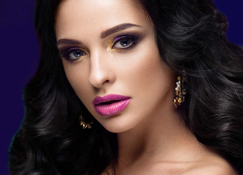 紫色背景下化彩妆的年轻女性