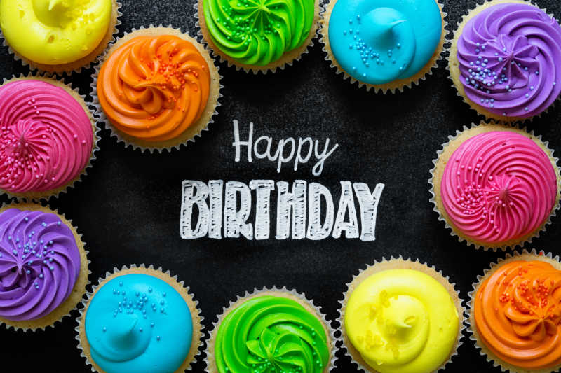 写在黑板上的生日快乐和周围的彩色蛋糕