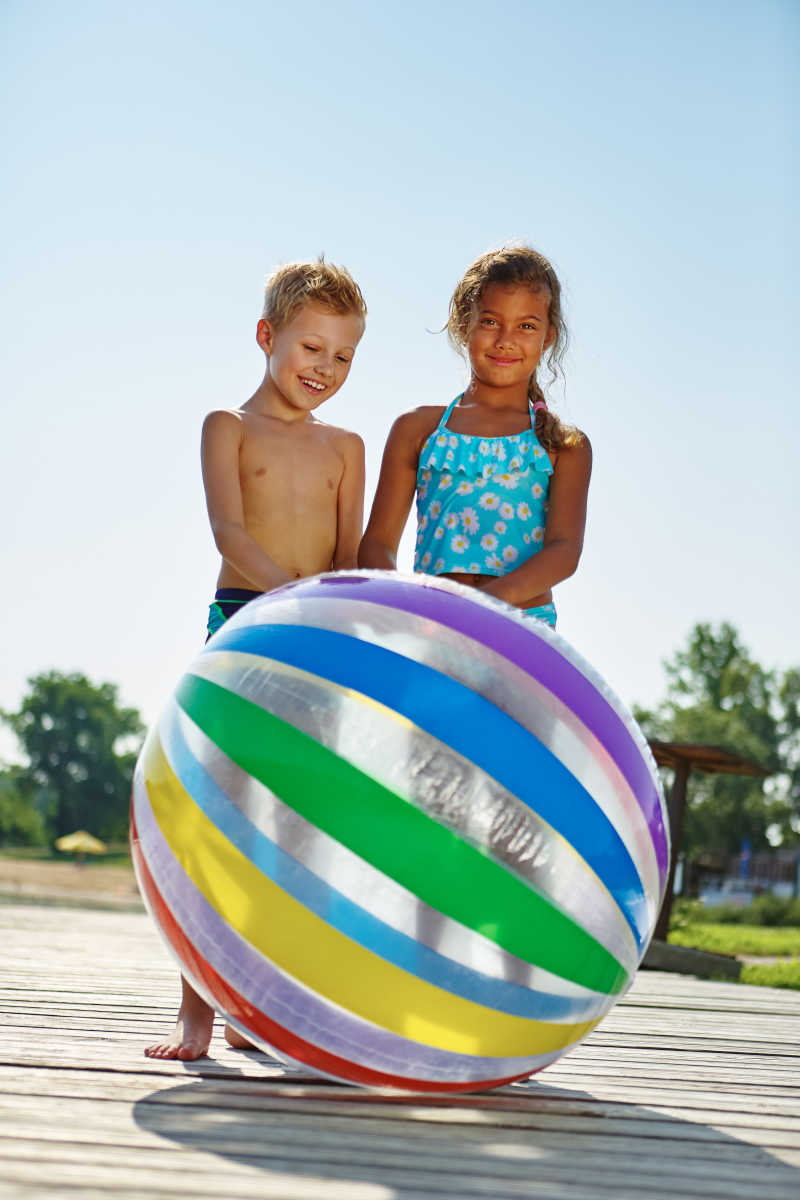 两个快乐的孩子在推一个大皮球