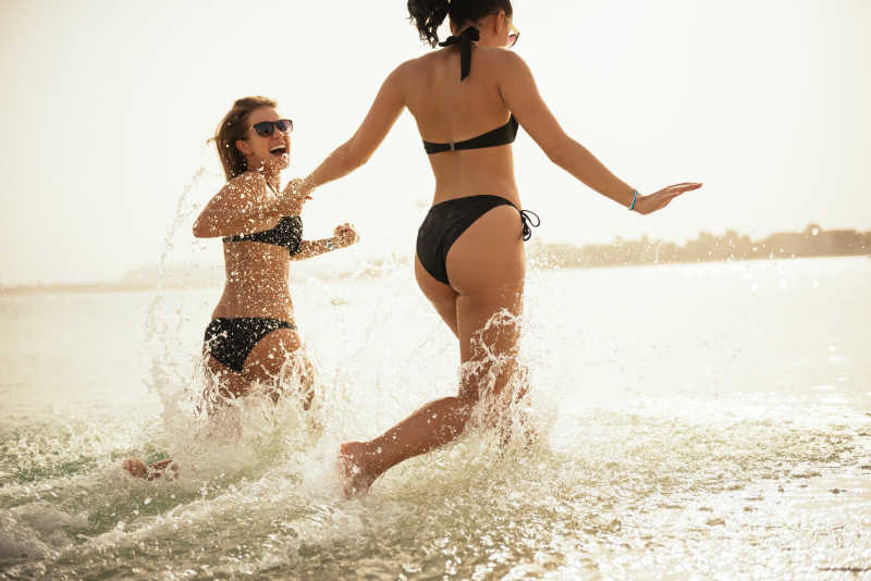 两个迷人的女人在海滩上跑步