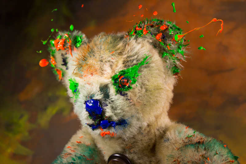 玩具熊上沾满了绿色和橙色颜料
