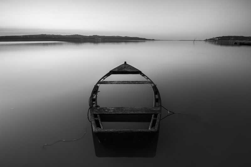 灰色背景下湖上的一艘孤舟