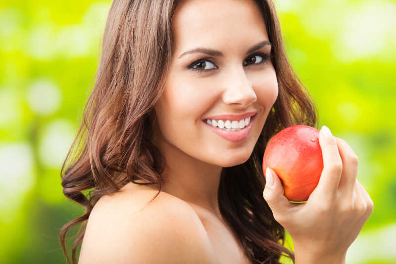 年轻快乐的微笑女人与苹果