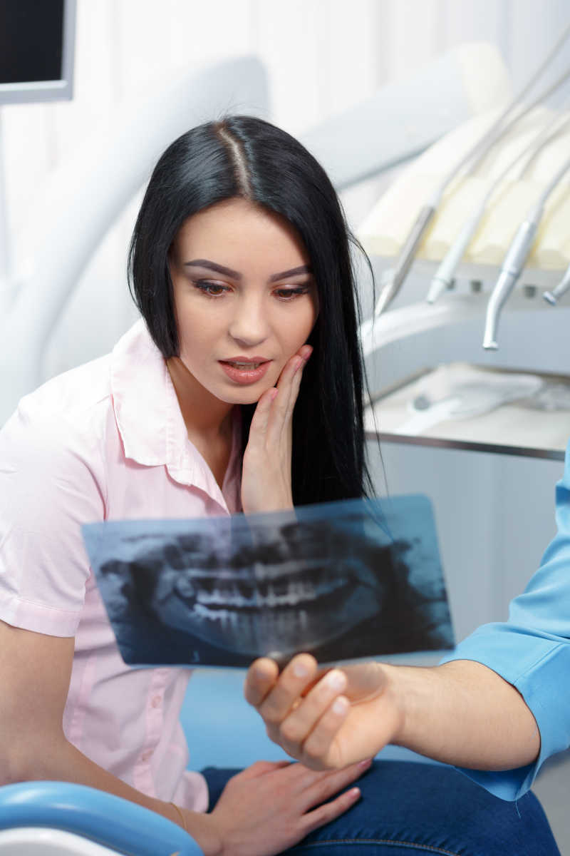 给牙科病人看X光照片的牙医