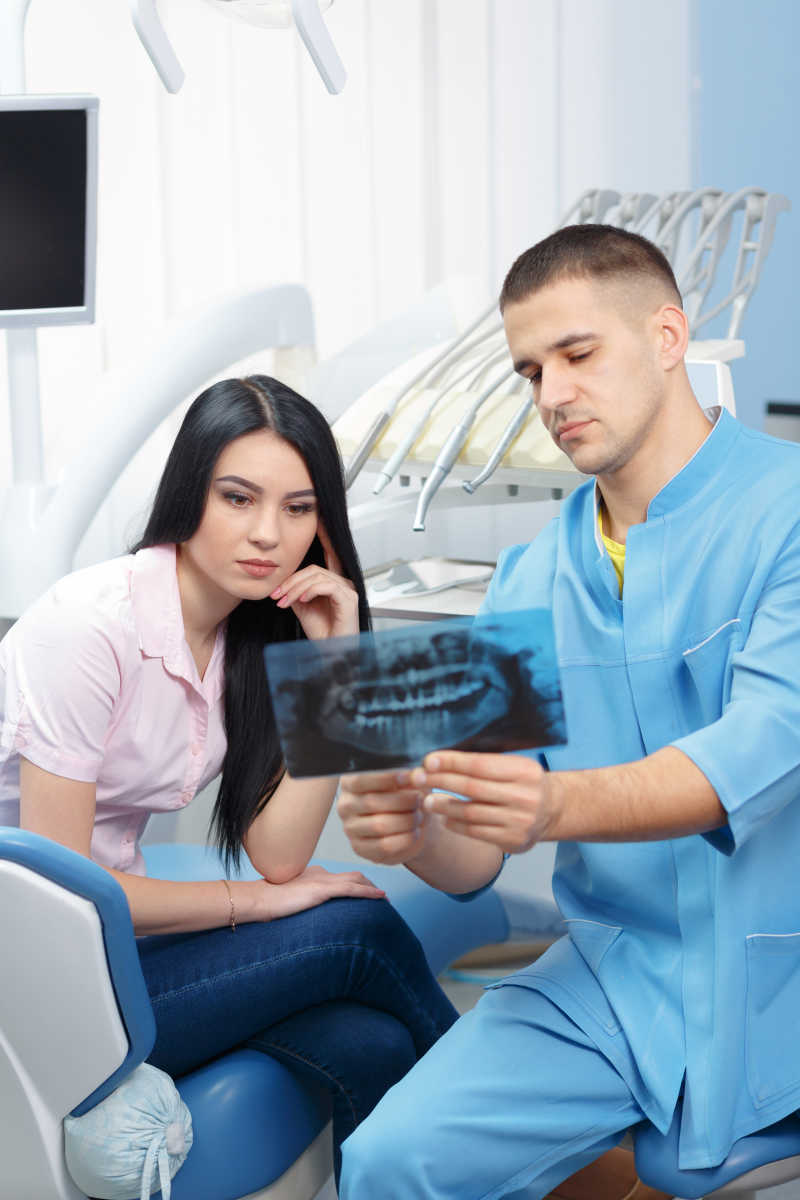 男性牙科医生给患者看X光照片