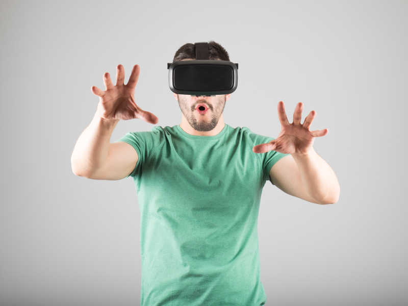 灰色背景下穿绿色T恤带3D虚拟眼镜的男人