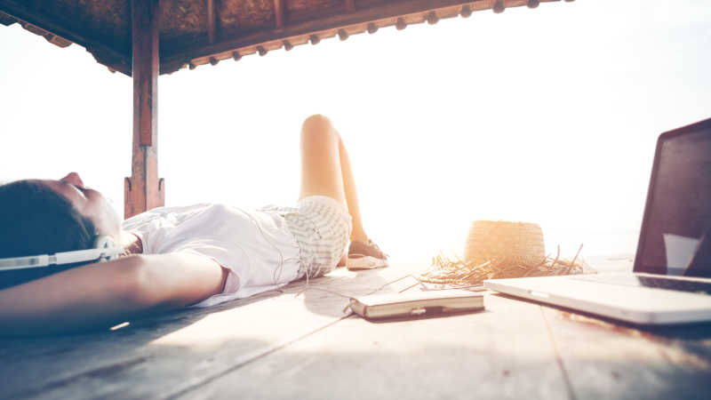 躺在海边亭子里的木板上休息听音乐的女人