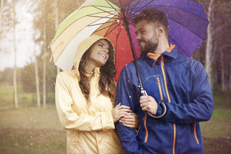 情侣夫妇在下雨天撑着彩虹伞