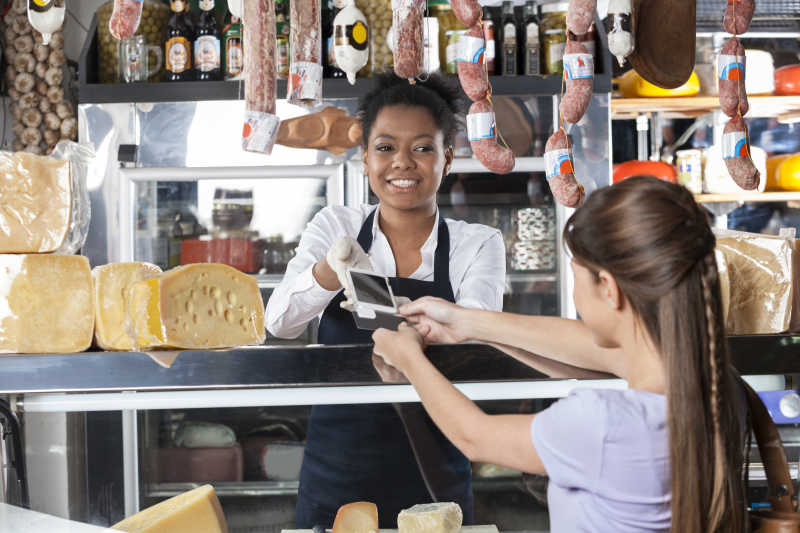 奶酪店里女售货员正在接受顾客的信用卡付款