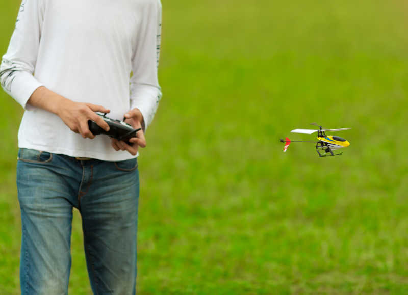 草地上年轻人拿着遥控飞机控制飞机模型飞行