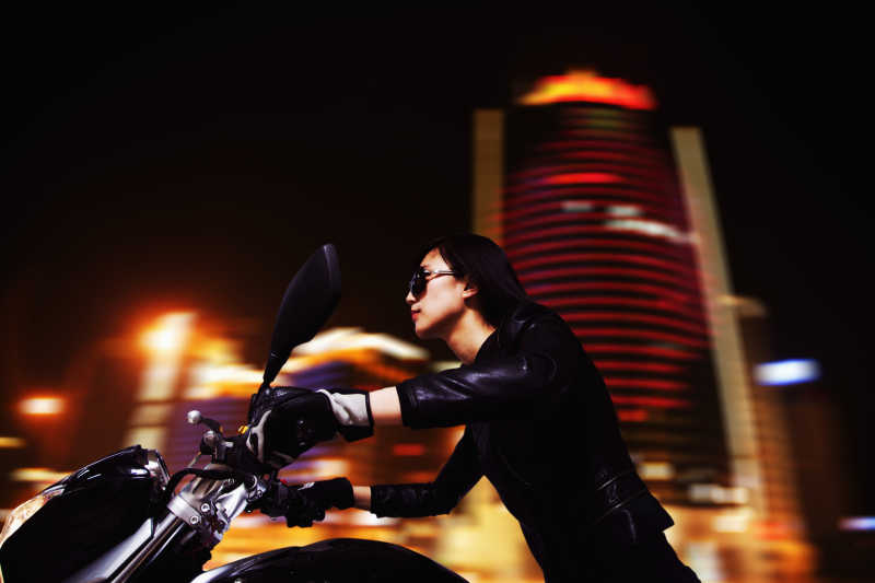 夜空下骑着摩托穿梭在灯火辉煌的城市里的年轻女子