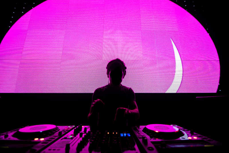 舞台上粉色屏幕前的音乐DJ