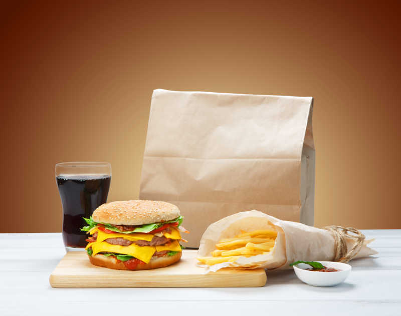 汉堡包套餐与薯条可乐在棕色袋子旁