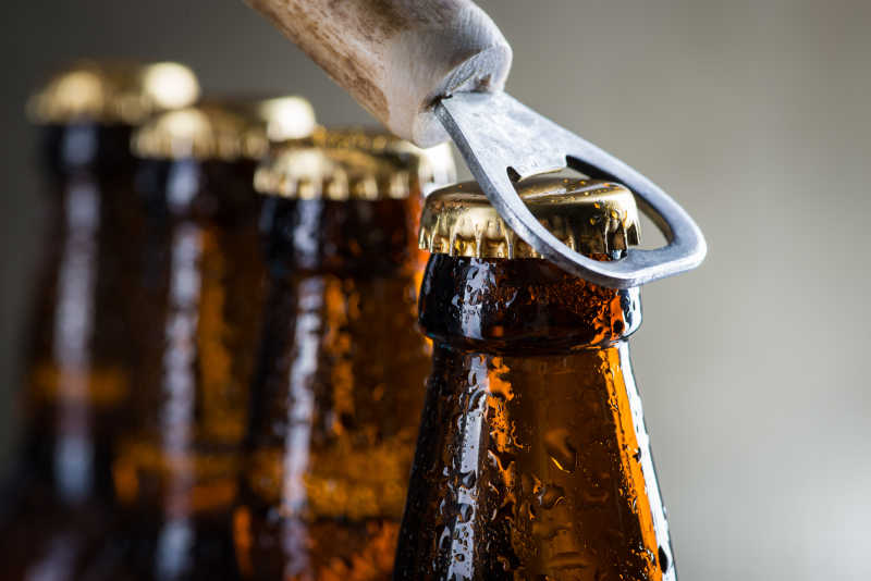 棕色冰啤酒瓶和旧开瓶器