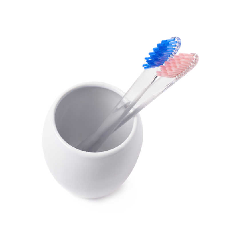 白色陶瓷杯中有蓝色和粉色鬃毛的两支牙刷