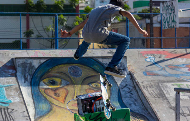 城市里在公园有涂鸦的场地玩滑板跳跃的人
