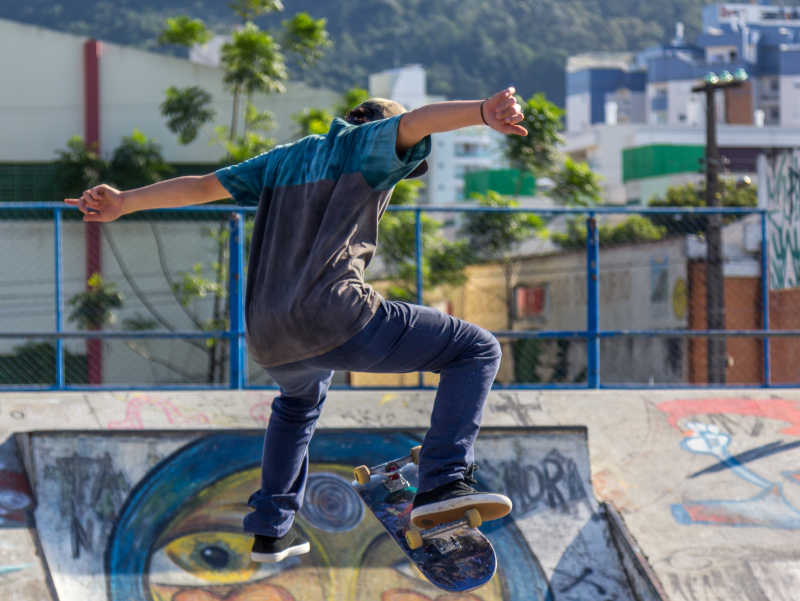城市里在有涂鸦的场地玩滑板飞起的年轻人