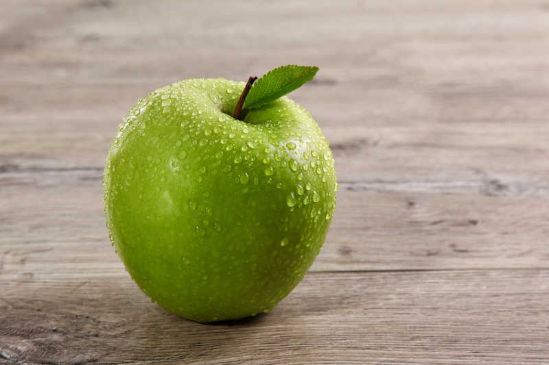 木桌上的绿色叶子青苹果
