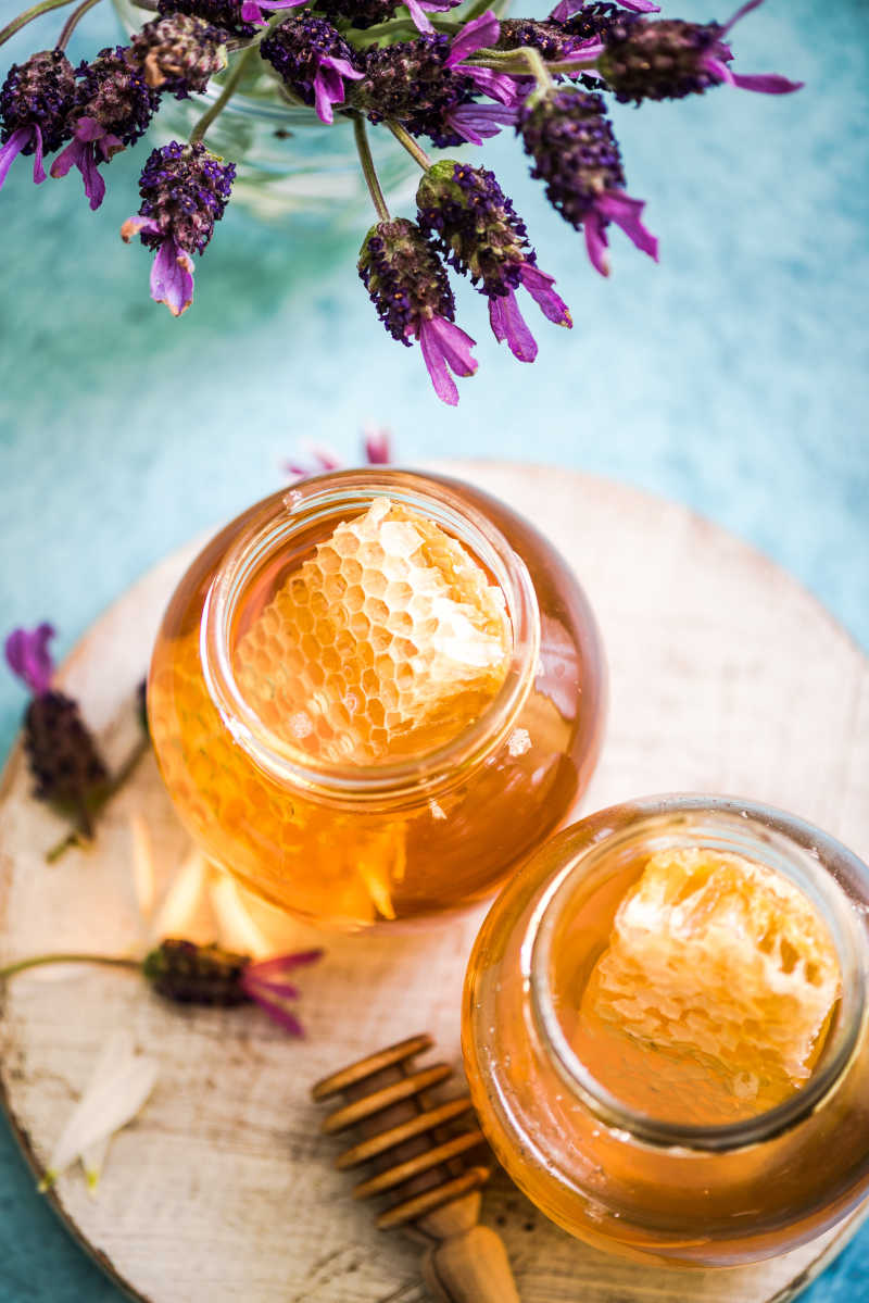 木制背景下的两瓶蜂蜜和薰衣草