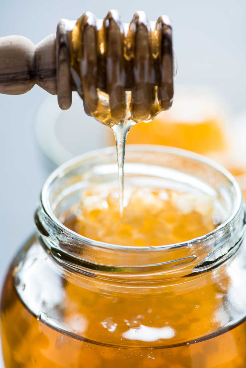 用木制蜂蜜勺倒入瓶子里蜂蜜