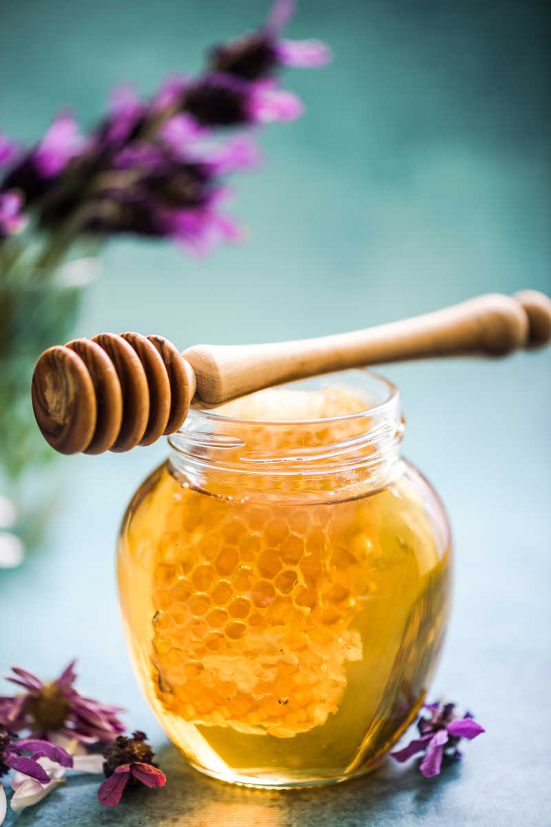 薰衣草背景下的新鲜蜂蜜和木勺