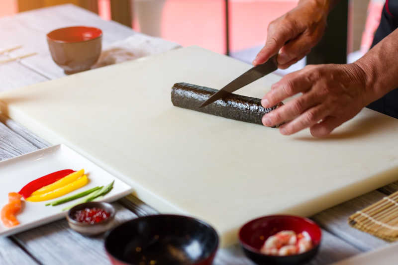 用刀子切开寿司卷的日本厨师