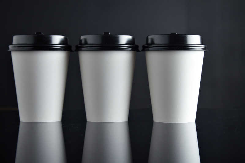 黑色背景下的三个白色纸质咖啡杯