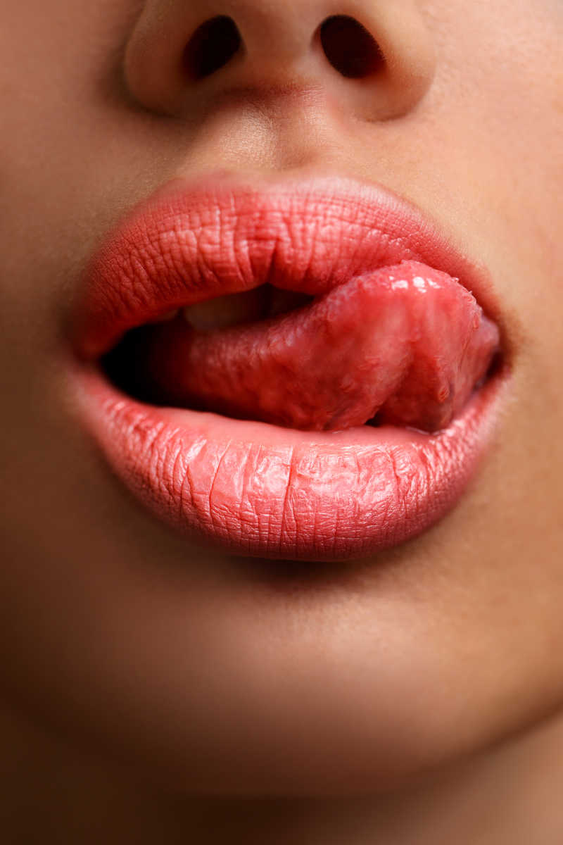 涂粉橘色唇膏的嘴唇诱惑的吐出舌头