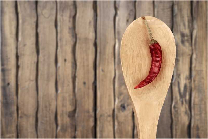 木制背景下的木勺里的辣椒