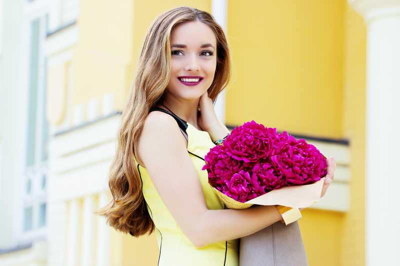 年轻漂亮的金发女孩捧着一束鲜花