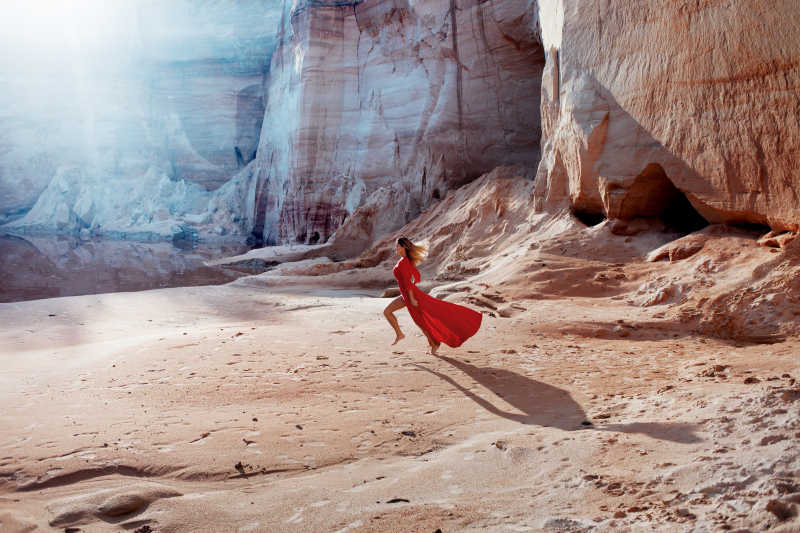在沙漠里的女子穿着飘动的红色连衣裙