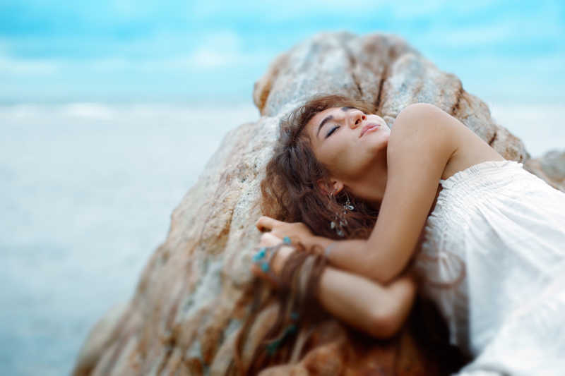 睡在海滩岩石上的年轻美女